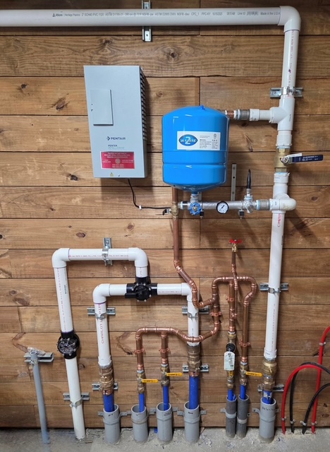 Well pressure controls, wiring, tank and plumbing installed on a utility wall